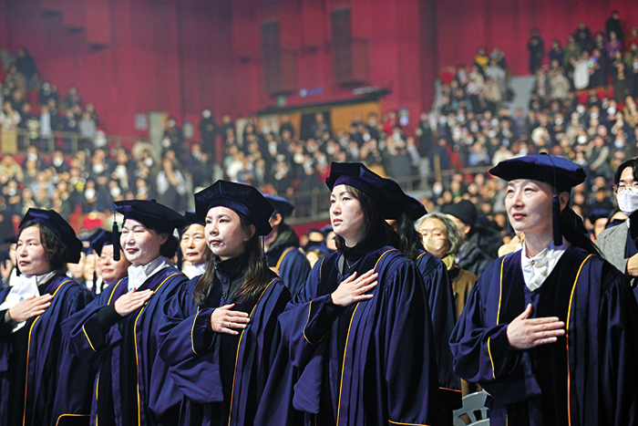 졸업생들이 경건한 모습으로 국민의례를 하고 있다.