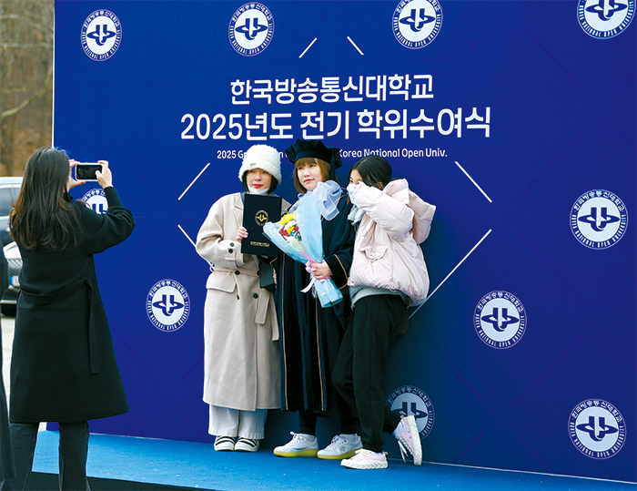 졸업생과 가족들이 졸업 기념 포토월에서 사진을 촬영하고 있다.